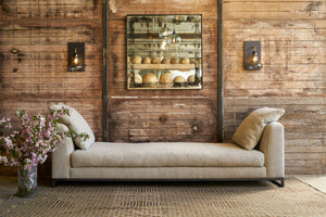  A daybed in front of a wood wall with a square mirror. Photographed in Andrews Burlap. 