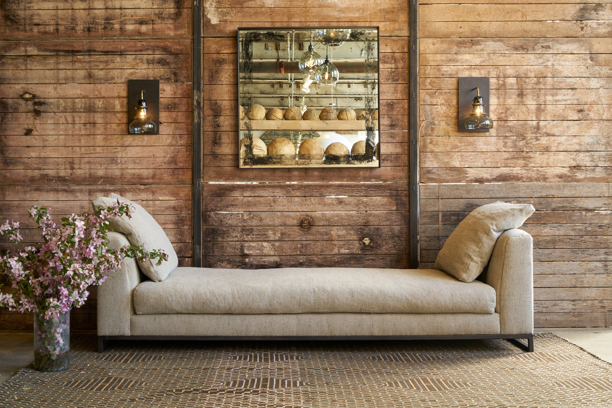  A daybed in front of a wood wall with a square mirror. Photographed in Andrews Burlap 