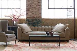  Sofa with 4 pillows in front of 2 large windows with a wing chair on the left. Photographed in Andrews Burlap 