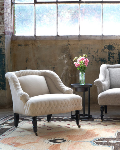 Chair in front of a window with a side table and pink flowers on top. Photographed in Vintage Flax.