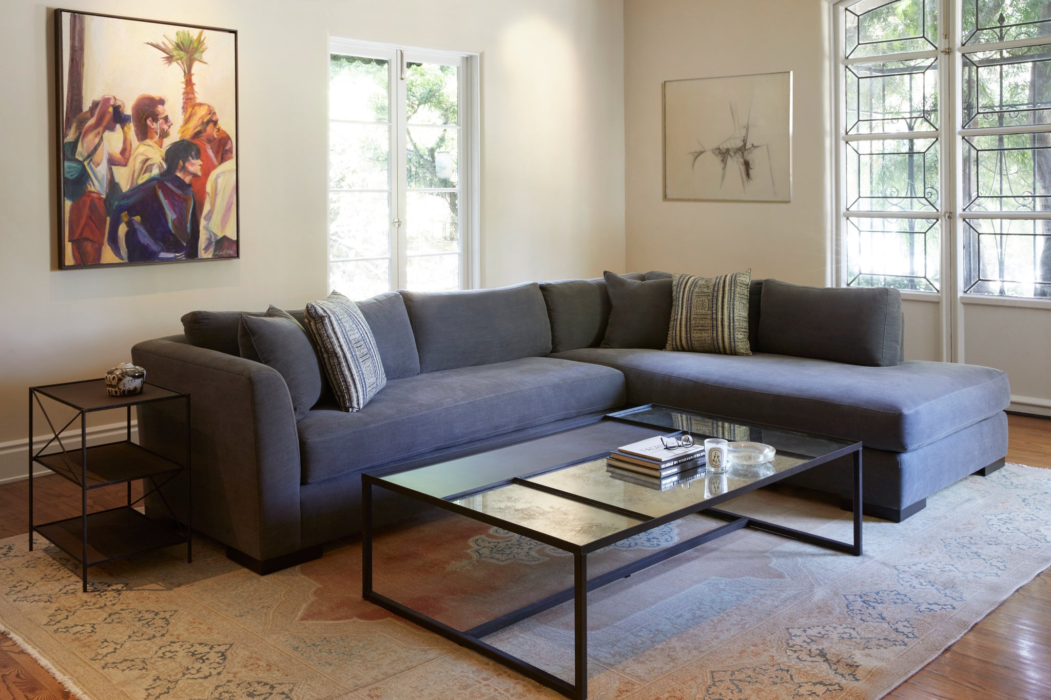 Ryder Sectional in Molino Slate next to a glass coffee table and a metal side table. Underneath the sectional we see a beige rug. Photographed in Molino Slate. 