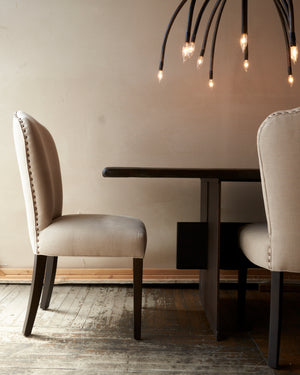  Saratoga chair in Logan Oatmeal next to a dining table. Above the table is a chandelier. Photographed in Logan Oatmeal. 