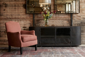  Rye Terra Sebastian chair in Rye Terra next to a dark credenza. In the background is a wood wall with two mirrors hanging. Photographed in Rye Terra. 