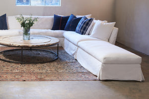  Seda bench in Denim White next to a white sofa and a wood coffee table in the center. Underneath all the pieces is a brown rug. Photographed in Denim White. 
