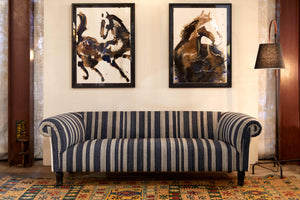  Springfield sofa in Rayas Indigo in front of a white wall with 2 paintings of horses. A Fairfax floor lamp on the right side. Photographed in Rayas Indigo. 