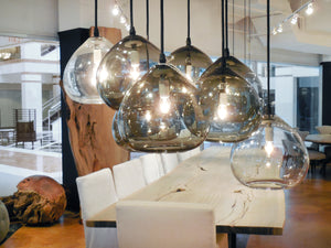  Cluster of teardrop pendants in clear and smoke. In the background is large dining table with slipcovered dining chairs.  