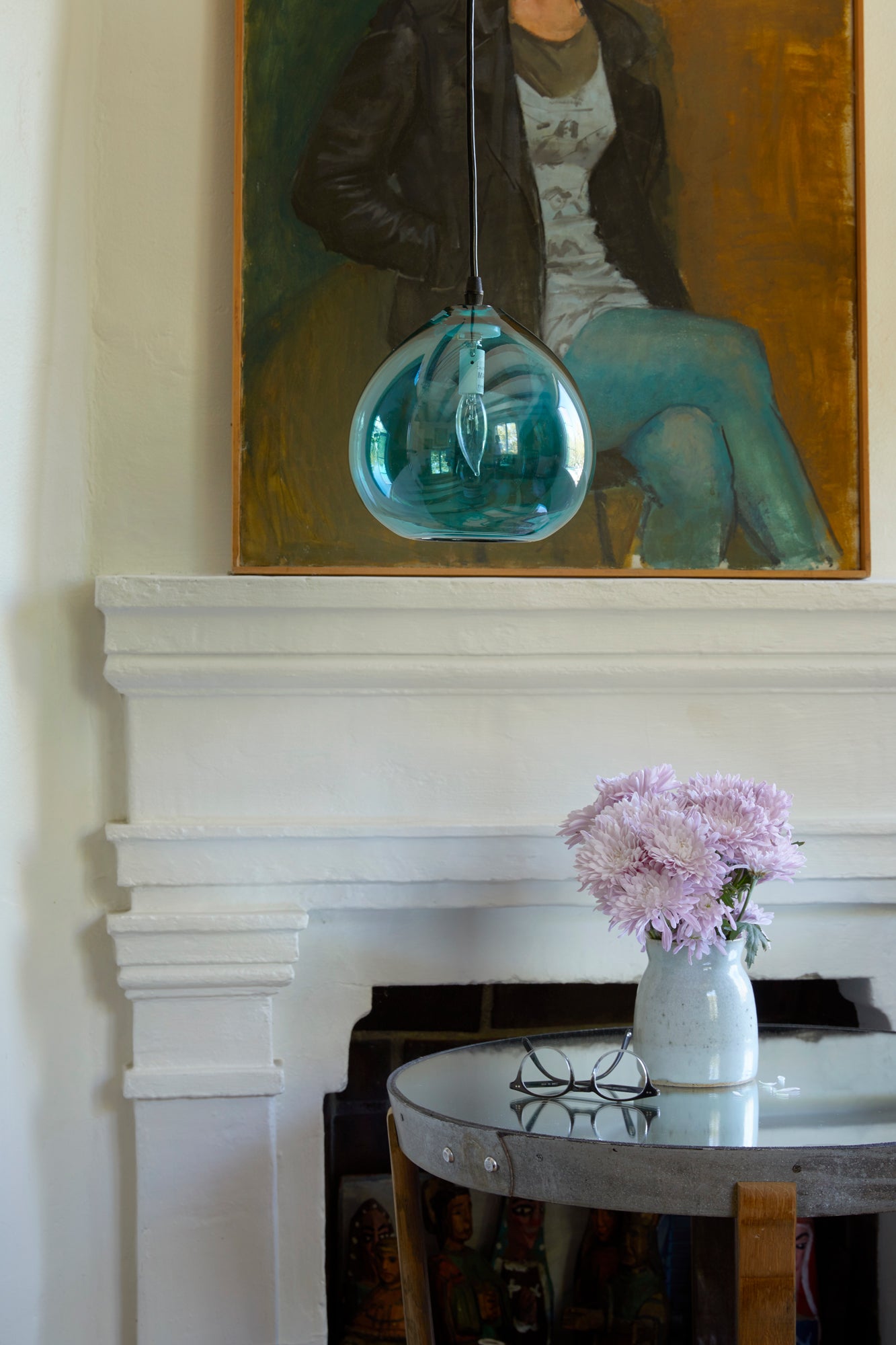  Teardrop pendant in turquoise hanging above winery side table in front of fire place with artwork on mantel. 
