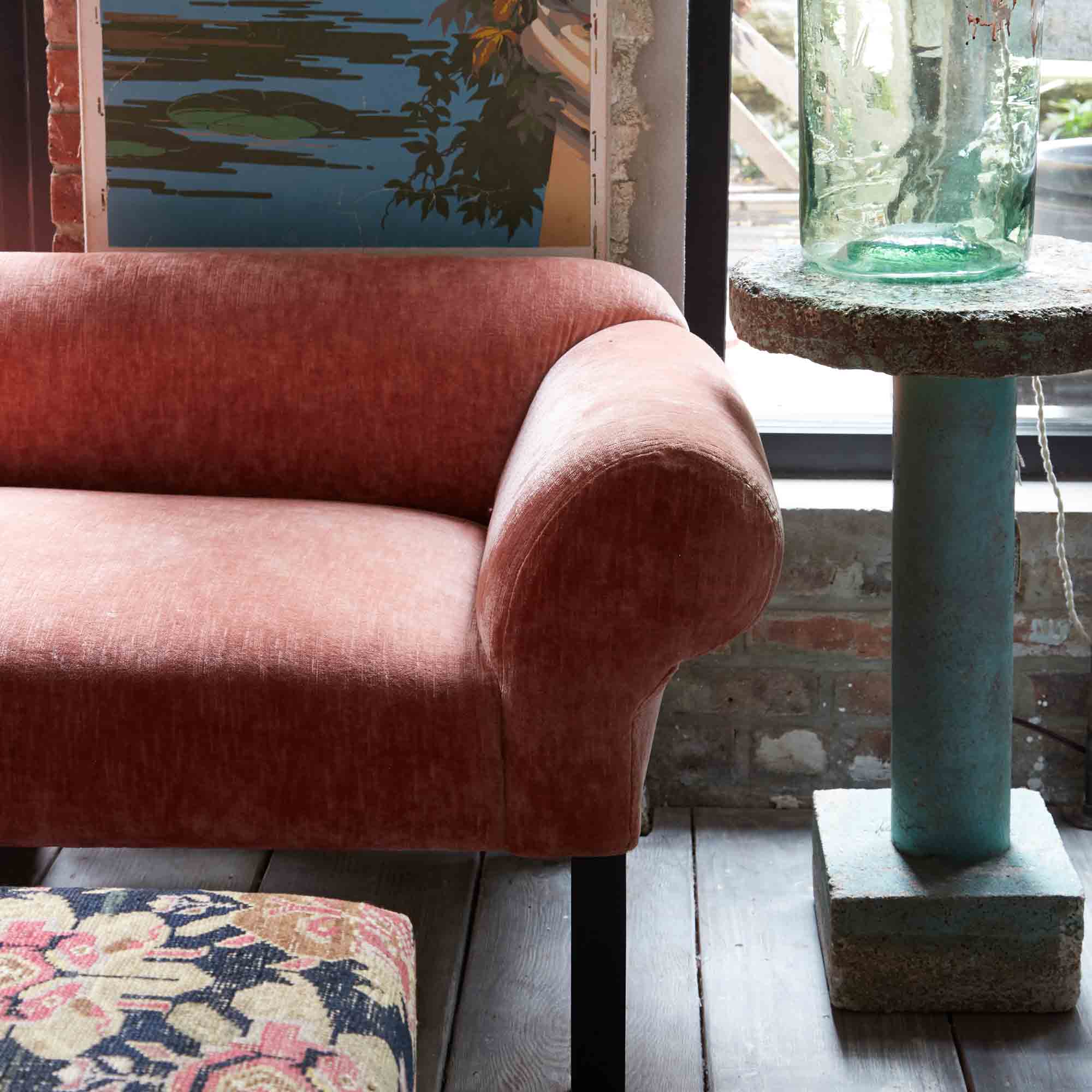  Detail of the Teddy sofa in Velluto Rose with a round side table on the right side and a painting in the back. Photographed in Velluto Rose. 
