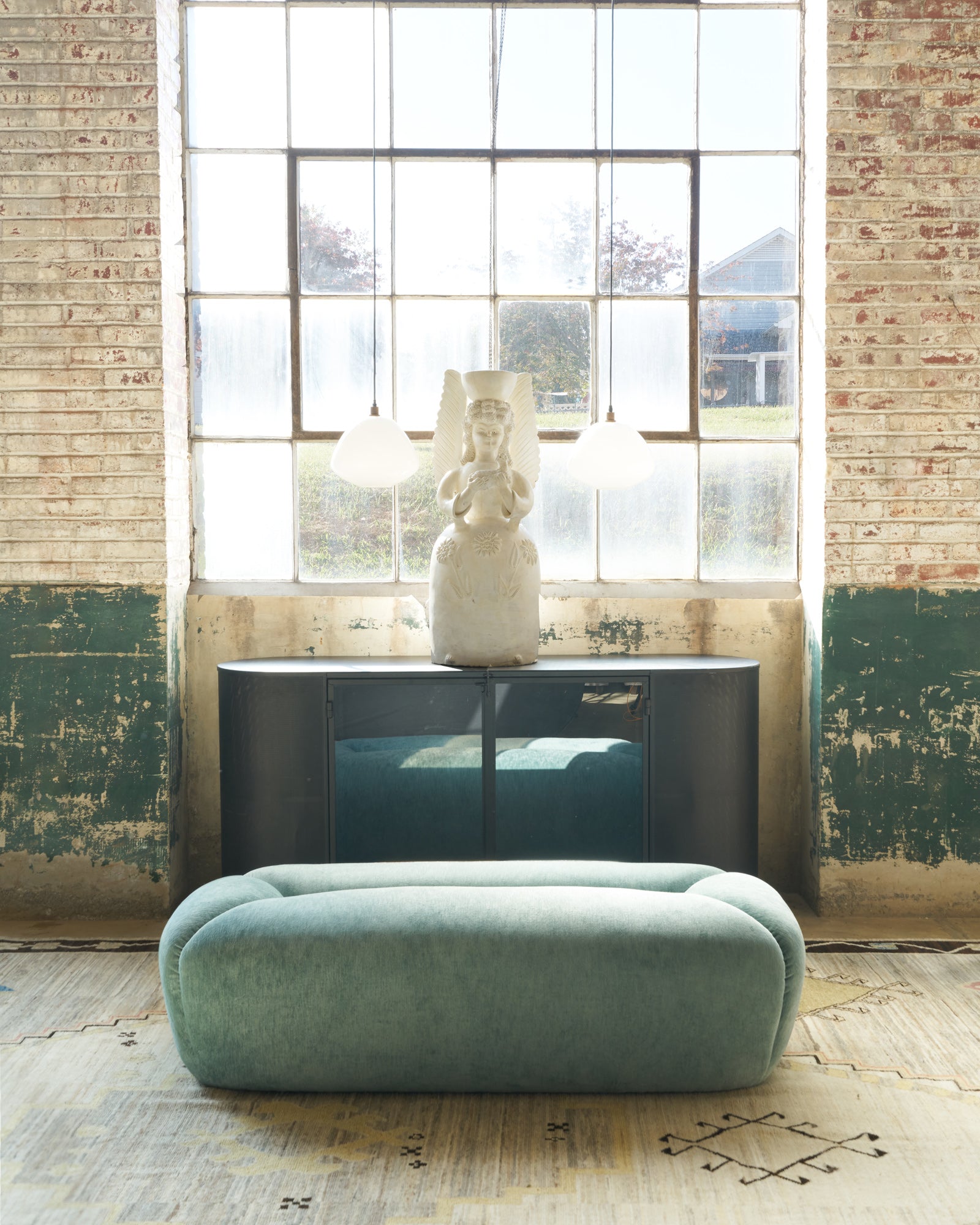  Bench in a showroom in front of a metal credenza with a sculpture on top. Photographed in Velluto Aqua. 