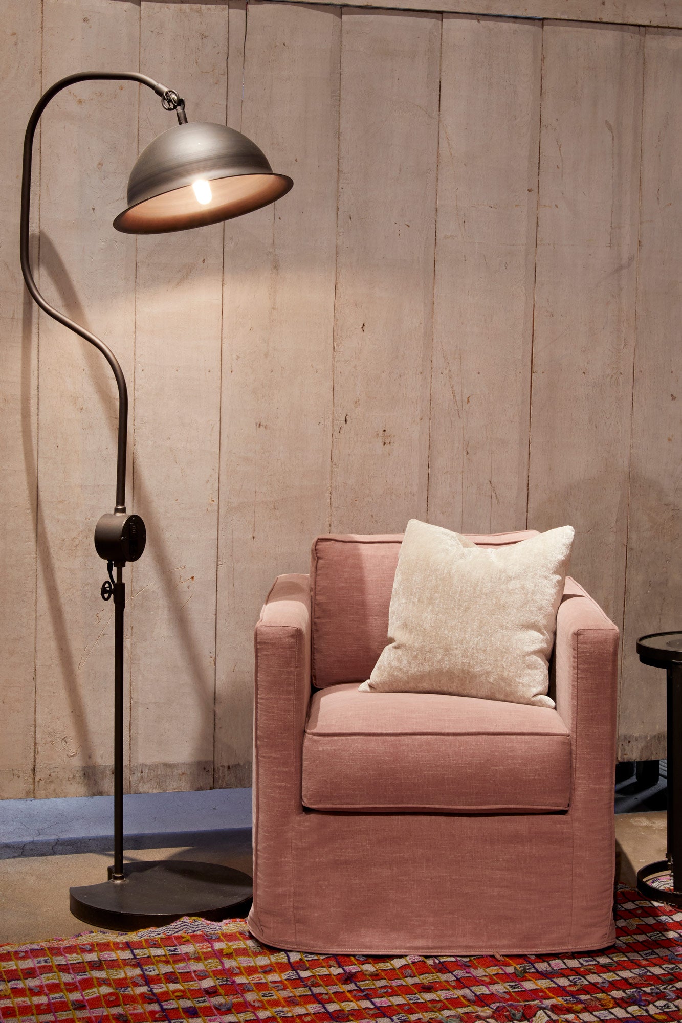  Vista mini chair in Molino Blush on top of a red rug next to a dark floor lamp. In the background are wood walls. Photographed in Molino Blush. 