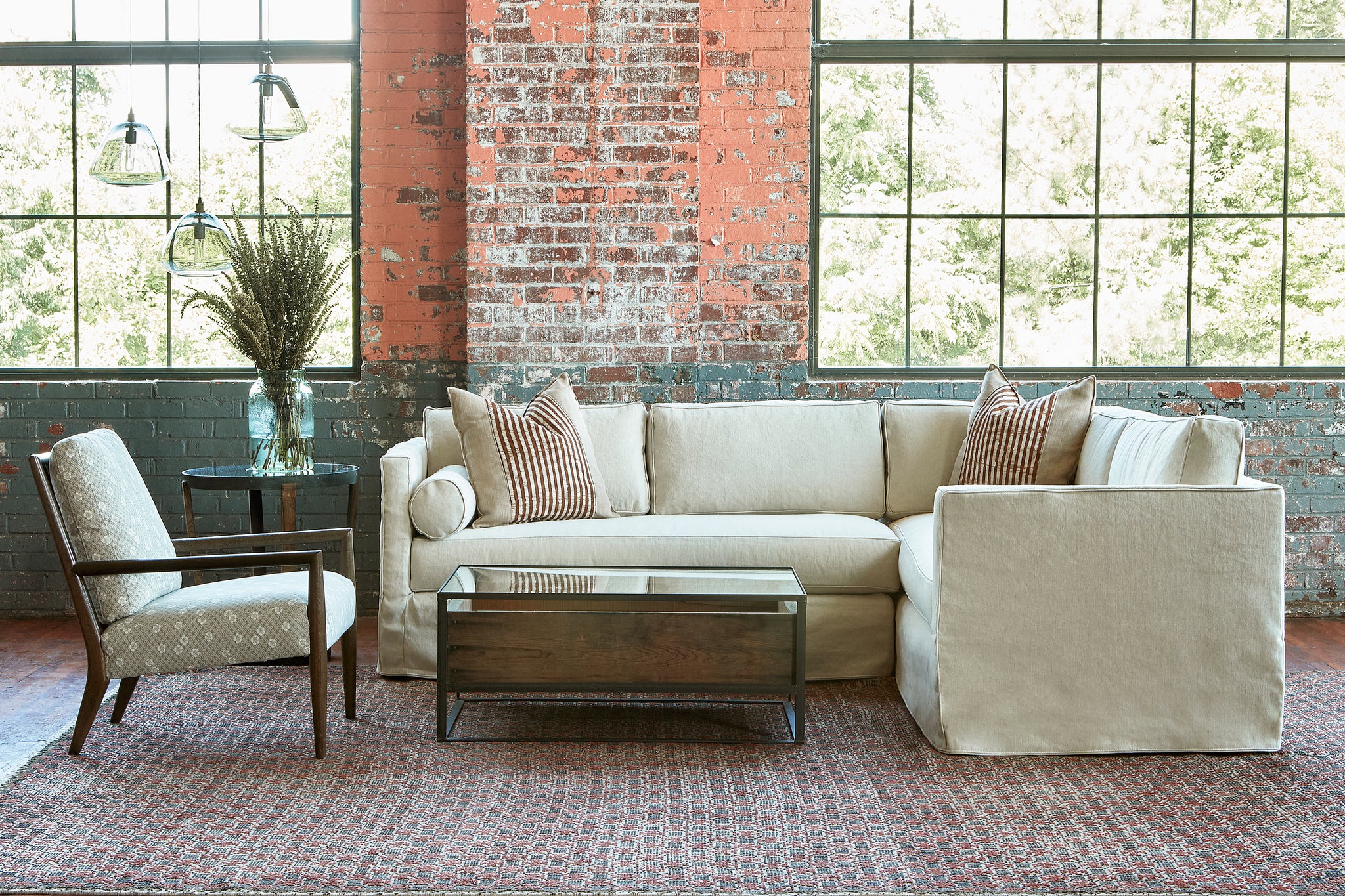  Cream colored sectional in an industrial showroom with a chair with flowers on the left and a wood and glass coffee table in front. Photographed in Vanocur Natural. 