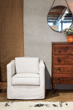  Vista Mini chair in Naomi White next to a wood credenza. In the background is patterned wall with a mirror hanging. Photographed in Naomi White. 